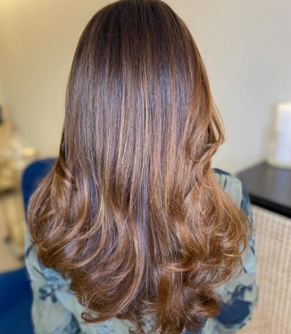Melena larga con ondas en las puntas y reflejos cobrizos